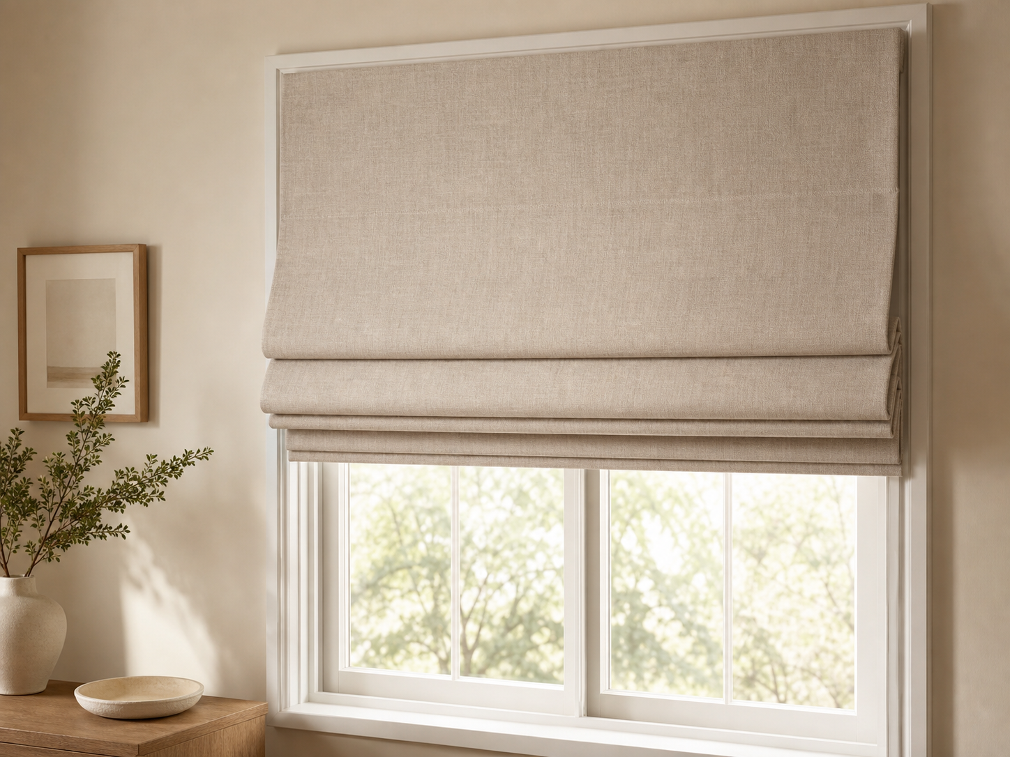 Cortina romana de tela beige plegada sobre ventana con pared cálida